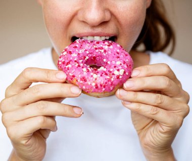 Pembe jöleli çörek yiyen bir kadının yakın çekimi..