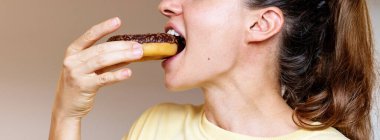 Çikolatalı çörek yiyen bir kadın.