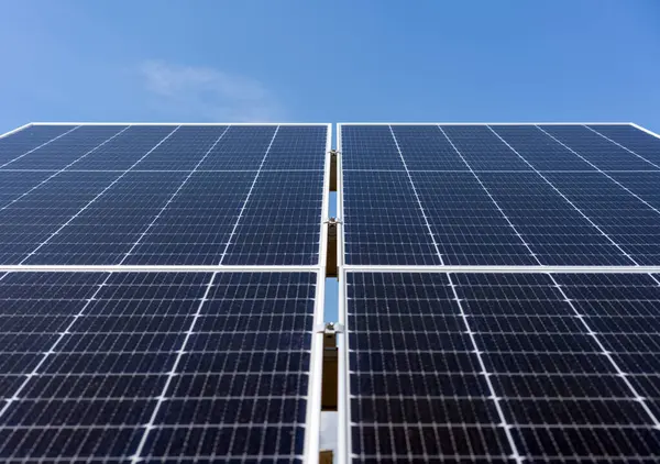Mavi gökyüzünün arka planında büyük endüstriyel güneş panelinin düşük açılı görüntüsü
