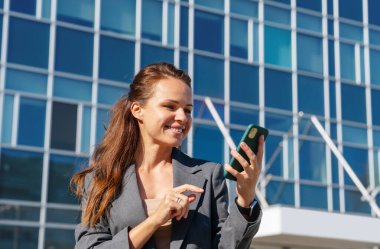 Kenar mahallede akıllı telefon kullanan kendine güvenen bir iş kadını.