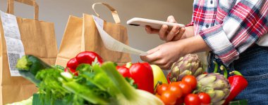 QR para makbuzunu tarayan kişinin bulanık arka planında taze sebzeler