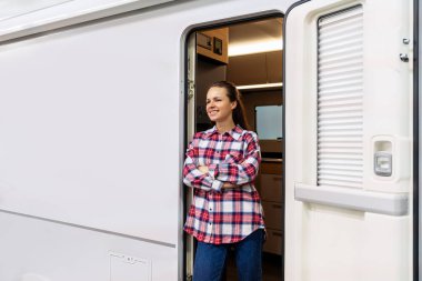 Kendine güvenen karavan sahibi karavan sahibi kollarını kavuşturup gülümsüyor.