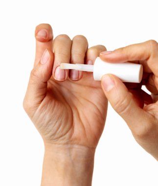 Beyaz arka planda tırnak altlarına nemlendirici yağ süren fırçalı bir kadın eli.