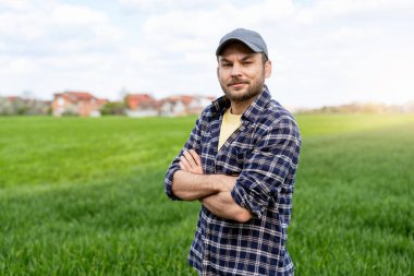 Yeşil kırsal alanda çapraz kollarla duran kendinden emin erkek çiftçi.