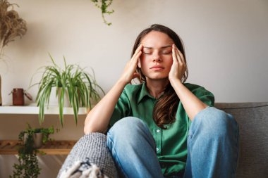 Stresli kadın kanepede oturuyor gözleri kapalı ve başı ellerinde.