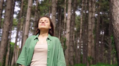 Genç ve mutlu bir kadın ormanda şehir kaçışından zevk alıyor.