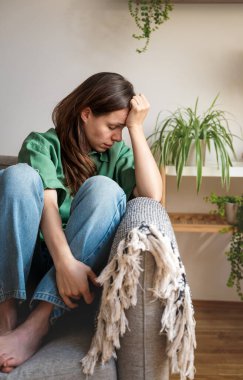 Yanmış bir kadın koltukta oturuyor ve kafası elinde dinleniyor.