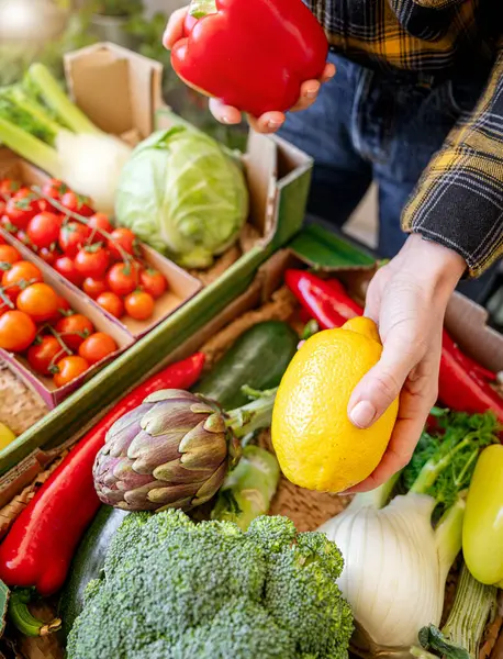 Kadın müşteri organik sebzeleri ve meyve kutularını açıyor.