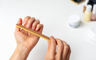 Close-up of woman using an emery board for nail care.	