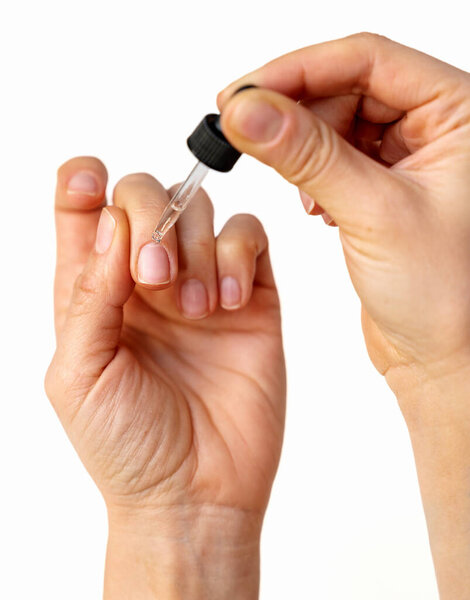 Крупный план женской руки нанесения кутикулярного масла на натуральные ногти с помощью капельницы.