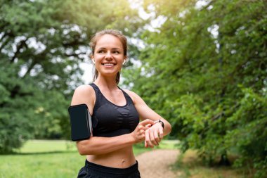 Akıllı telefonu ve akıllı kaseti olan aktif bir kadın dışarıda antremana hazırlanıyor..