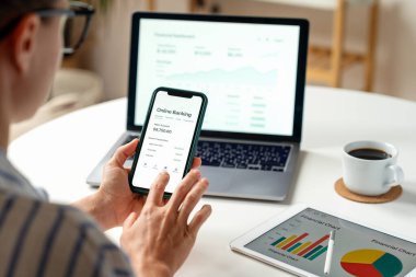 Akıllı telefon ve dizüstü bilgisayarla dijital bankacılık hizmetlerine erişen kadın kullanıcı