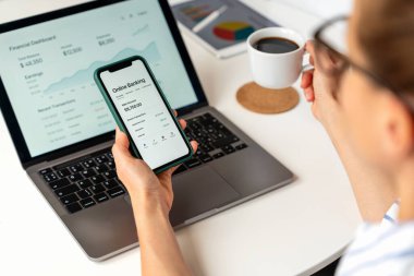 Bilgisayarı ve akıllı telefonu kullanarak evdeki internet bankacılığı uygulaması ile finansmanı yöneten kadın