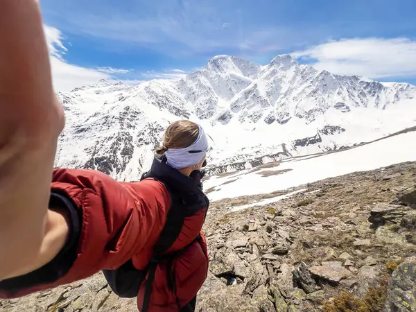 Dişi yürüyüşçü, dağ yolunda panoramik manzaralı selfie çekiyor.