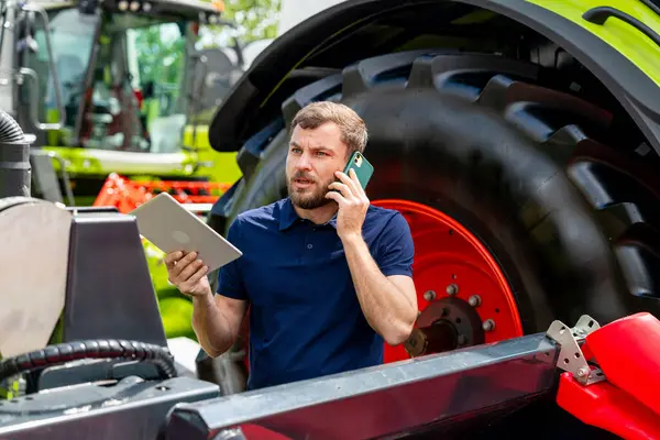 Tarım sektörü profesyoneli tablet tutuyor ve tarım galerisinde telefonla konuşuyor.