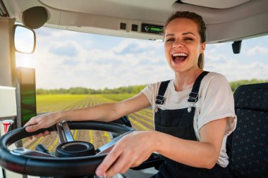 Tarlada traktör süren mutlu kadın çiftçi.