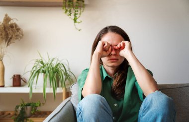 Üzgün kadın ağlıyor ve yumruklarıyla gözlerini ovuşturuyor..