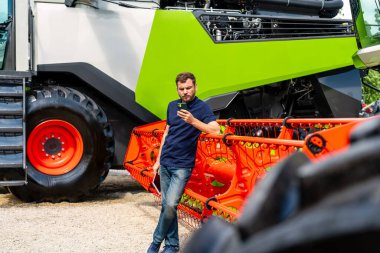 Satıcının başlığının yanındaki akıllı telefonu kontrol eden kendinden emin tarım uzmanı