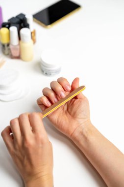 Beyaz arka planda tırnak törpüsü kullanan kadın