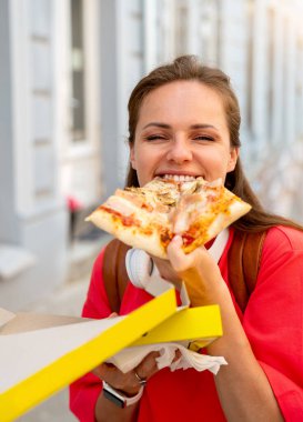 Şehirdeki pizzayı seven genç bir kadın.