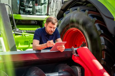 Tarımsal ekipman bayiliğinde hasatçıyı birleştirerek tableti kontrol eden adam