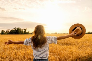 Mısır gevreği tarlasında altın saatinde doğayı ve özgürlüğü kucaklayan genç bir kadın