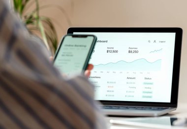 Dizüstü bilgisayarda dijital bankacılık ve kadının cep telefonu.