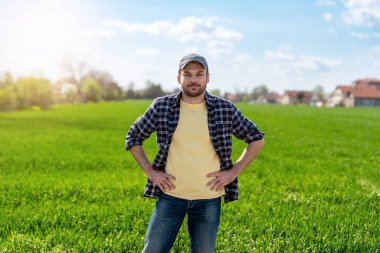 İlkbahar mevsiminde yeşil mısır gevreği tarlasının yanındaki kırsal adamın portresi