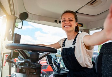 Çiftlik malzemeleri deposunda traktör kabininde selfie çeken kadın bir çiftlik işçisi..