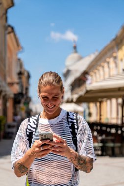 Avrupa şehir caddesinde gezerken akıllı telefon kullanan trend genç şehir kadını
