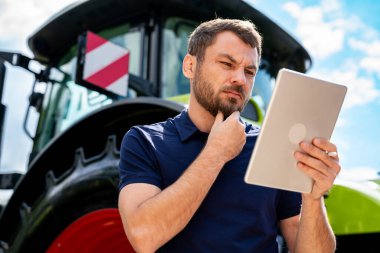 Tarımsal bayilikte traktörle tablet okuyan odaklı adam