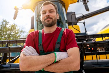 Tarım makineleri operatörünün portresi biçerdöverin önünde güvenle duruyor