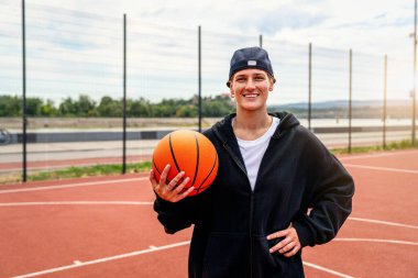 Şehirdeki sokak topu sahasında basketbolla poz veren genç aktif kadın..