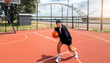 Sokak sahasında basketbol oynayan aktif genç bir kadın.