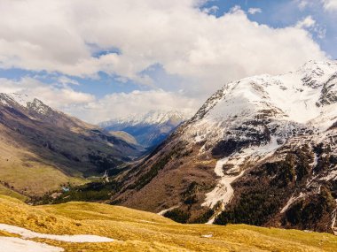 Elbrus dağlarının karlı zirveleri mavi gökyüzünün altında ve ilkbaharda beyaz bulutlar.