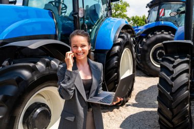 Çiftlik makinelerinde dizüstü bilgisayarı ve akıllı telefonu olan profesyonel bir tarım işçisi.