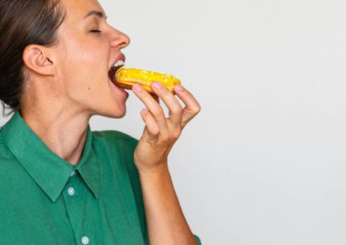 Yeşil gömlekli kadın, sarı jöleli donut yiyor.