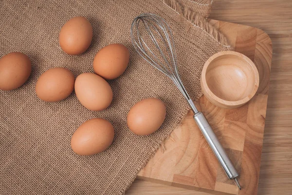 stock image Kitchen metal wire and raw eggs on the wooden board