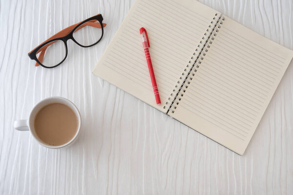 Workplace with note, paper, pen and cup of coffee on work table. Top view shot