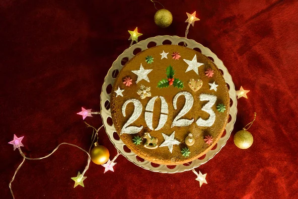 2023年のお正月ケーキ 赤いベルベットのテーブルクロスに星型のクリスマスライトとベビール ストック画像