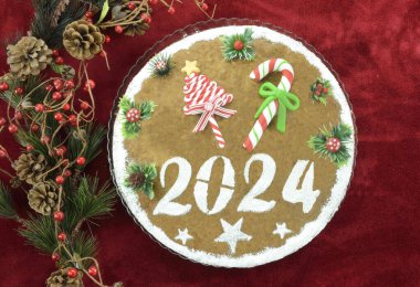 2024 yılbaşı pastası ve kırmızı arka planda yapay Noel süslemeleri