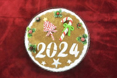 Yeni yıl pastası, vasilopita olarak bilinen, kırmızı kadife masa örtüsü üzerine 2024 yılı için