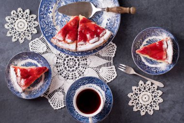 Mavi tabakta kırmızı çilekli Noel turtası ve masada kırmızı bir kutuda hediye, bembeyaz örülmüş peçetelerin üzerinde bembeyaz renkli yiyecekler, kar taneleri şeklinde, kış havası. Yüksek kalite fotoğraf