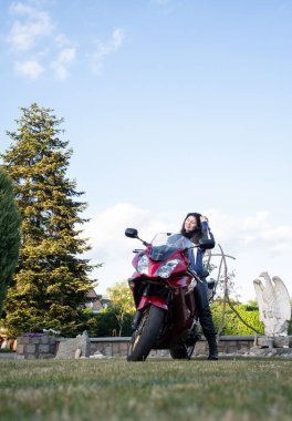 Motosikletli güzel, esmer bir motosikletli genç kız, mesafeye bakıyor ve gülümsüyor.