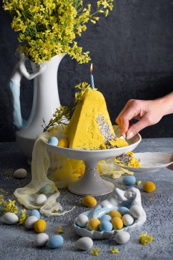 Geleneksel Paskalya Ortodoks pastası, gri bir masada sarı çiçekler, yüksek kaliteli fotoğraf.
