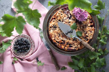 still life with delicious berry tart with almonds and black currants sprinkled with powdered sugar on a pink linen tablecloth, home bakking, top view High quality photo