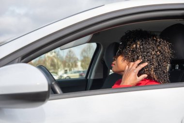 Pretty african woman in a car fixing her hair while standing in a traffic jam, concept a modern married business woman with children saves time, High quality photo