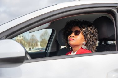 Pretty african woman in a car doing makeup while standing in a traffic jam, concept a modern married business woman with children saves time, High quality photo