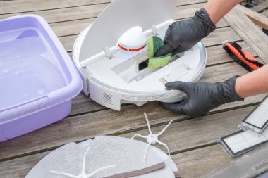 woman washing a trash can in a robot vacuum cleaner,planned maintenance of equipment for long-term use, High quality photo