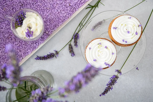 İki krem şantili lavanta çiçekleri ve kapuçinoyla süslenmiş kremalı kek.